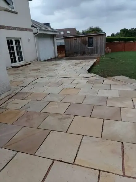 Indian sandstone patio after cleaning, beside a lawn