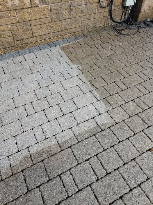 Tegular block paving mid-clean, the washed half clearly lighter than the untouched half