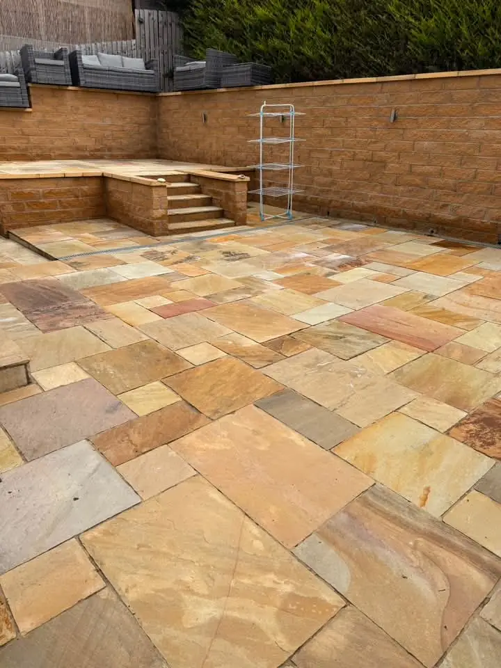 Cleaned Indian sandstone patio with a raised stone planter